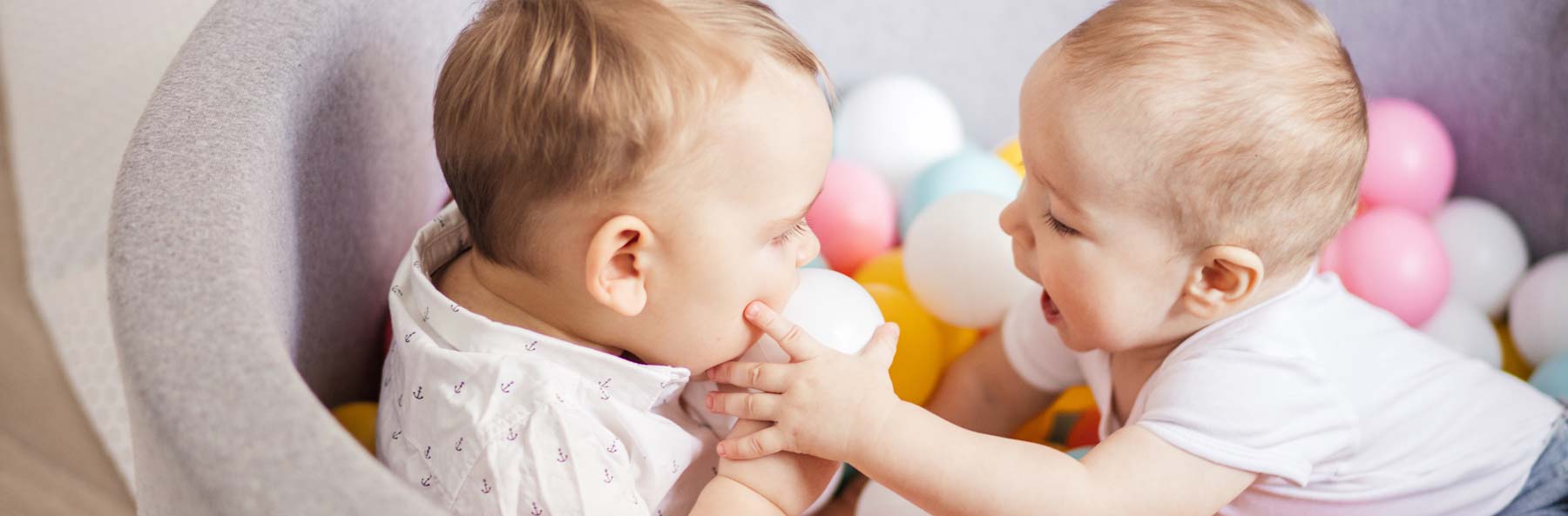 two babies playing in ball pit